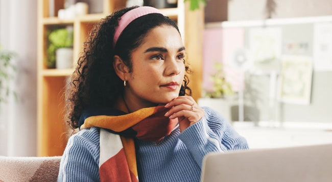 Woman working on a laptop while pausing to think